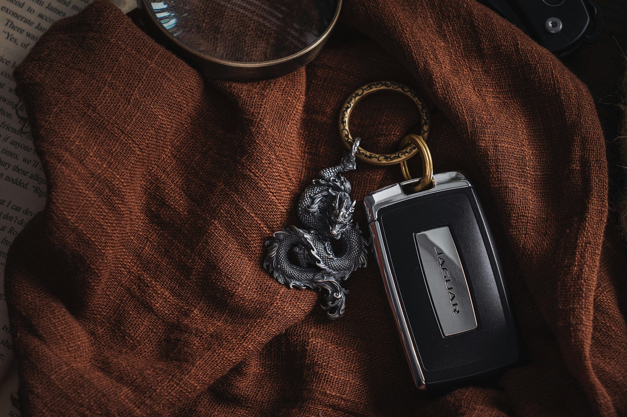 Stylish dragon keychain and car key on textured brown fabric, exuding luxury and sophistication.