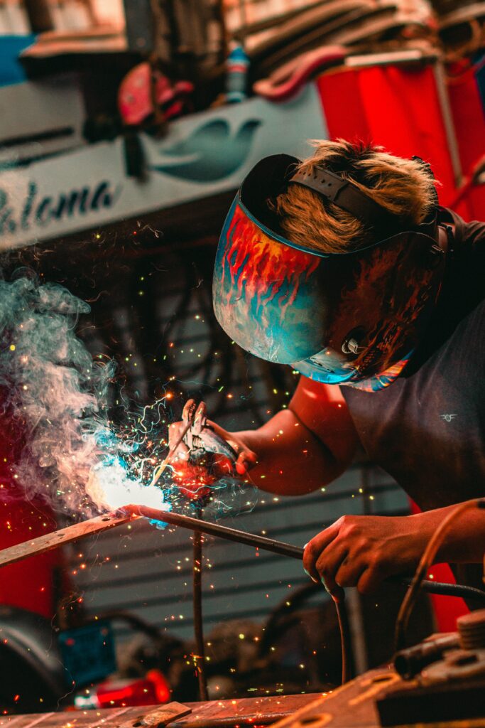 Close-up of a welder using safety gear and creating sparks in an industrial setting.