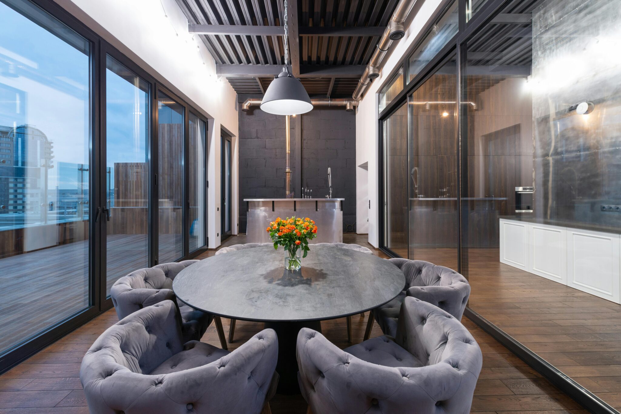 Interior of modern lounge zone with round table and comfortable armchairs placed near panoramic windows in evening time